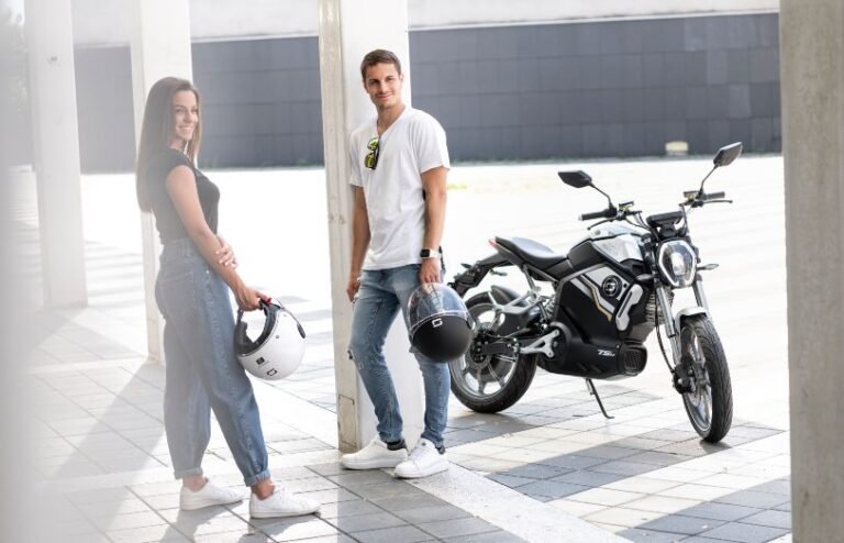young couple talking next to an electric super soco TSx motorcycle